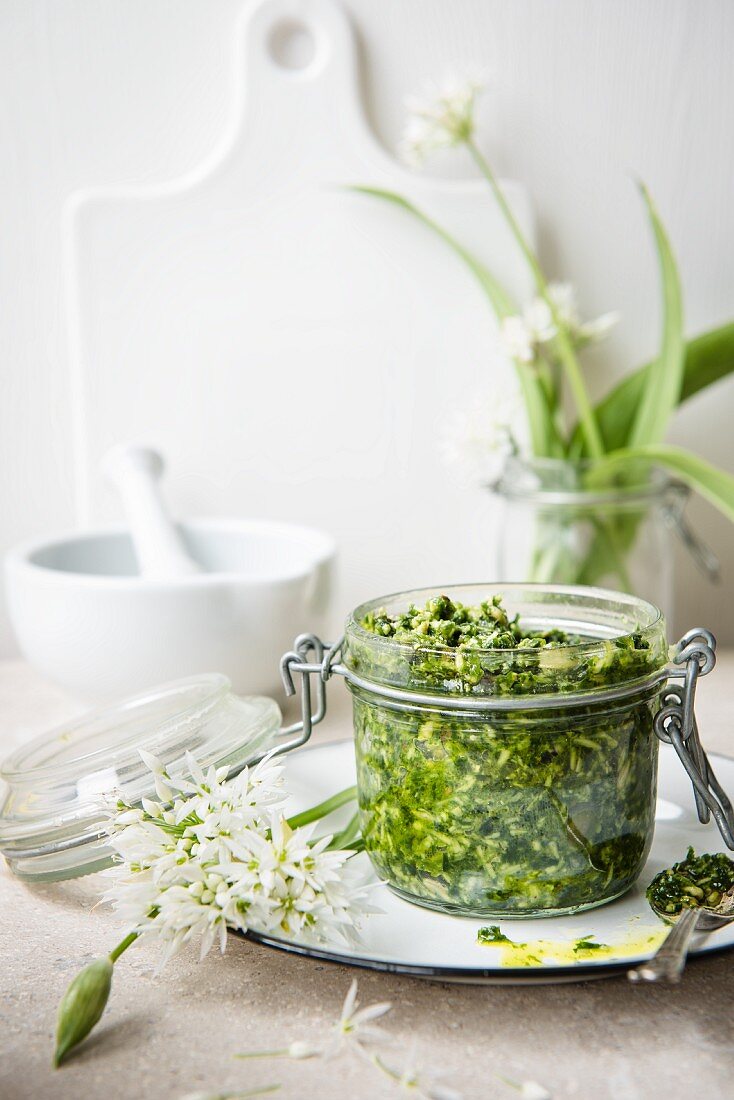 A jar of wild garlic pesto and fresh wild garlic with flowers