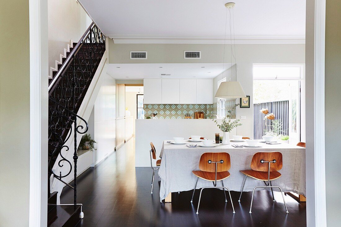 Classic wooden chairs at a set dining table in front of the kitchen area, to the side of the stairs