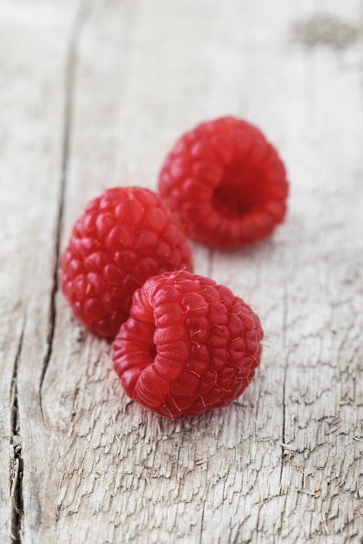 Three raspberries on a wooden surface