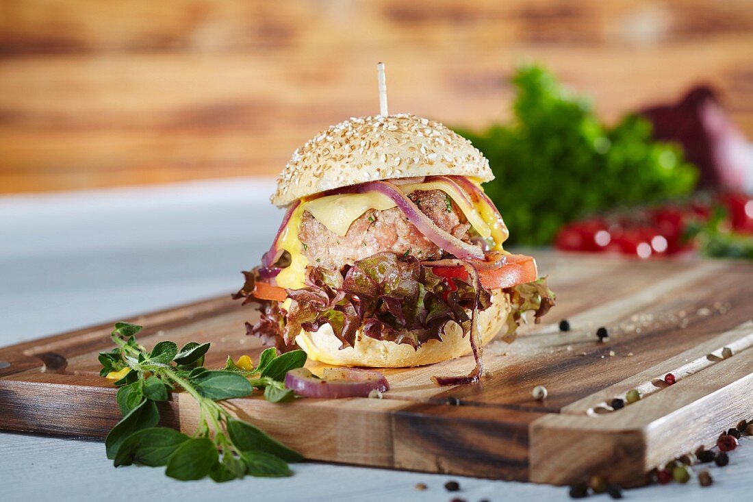 A mini hamburger with oak leaf lettuce, tomatoes, onions and cheese