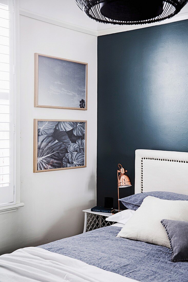 Bed with pillows and white headboard against black wall in bedroom