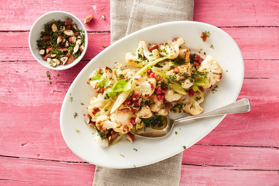 Crispy cauliflower with leaves, celery, pomegranate seeds and a cress and almond topping