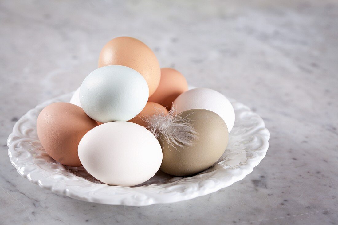 Frische Eier mit Feder auf Teller