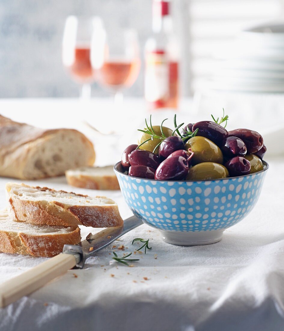 Kalamata-Oliven und grüne Oliven mit Brot und Rosewein auf gedecktem Tisch