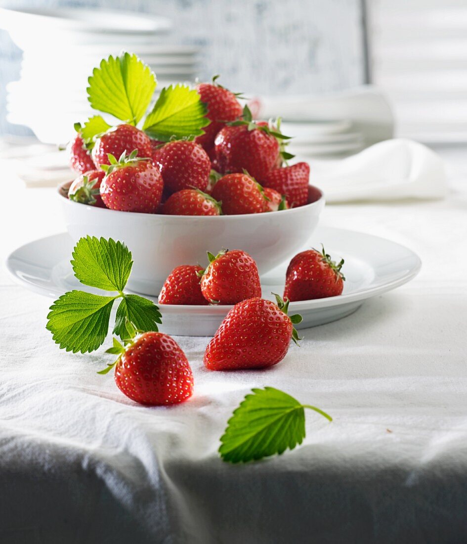 Fresh strawberries and leaves in a porcelain bowl
