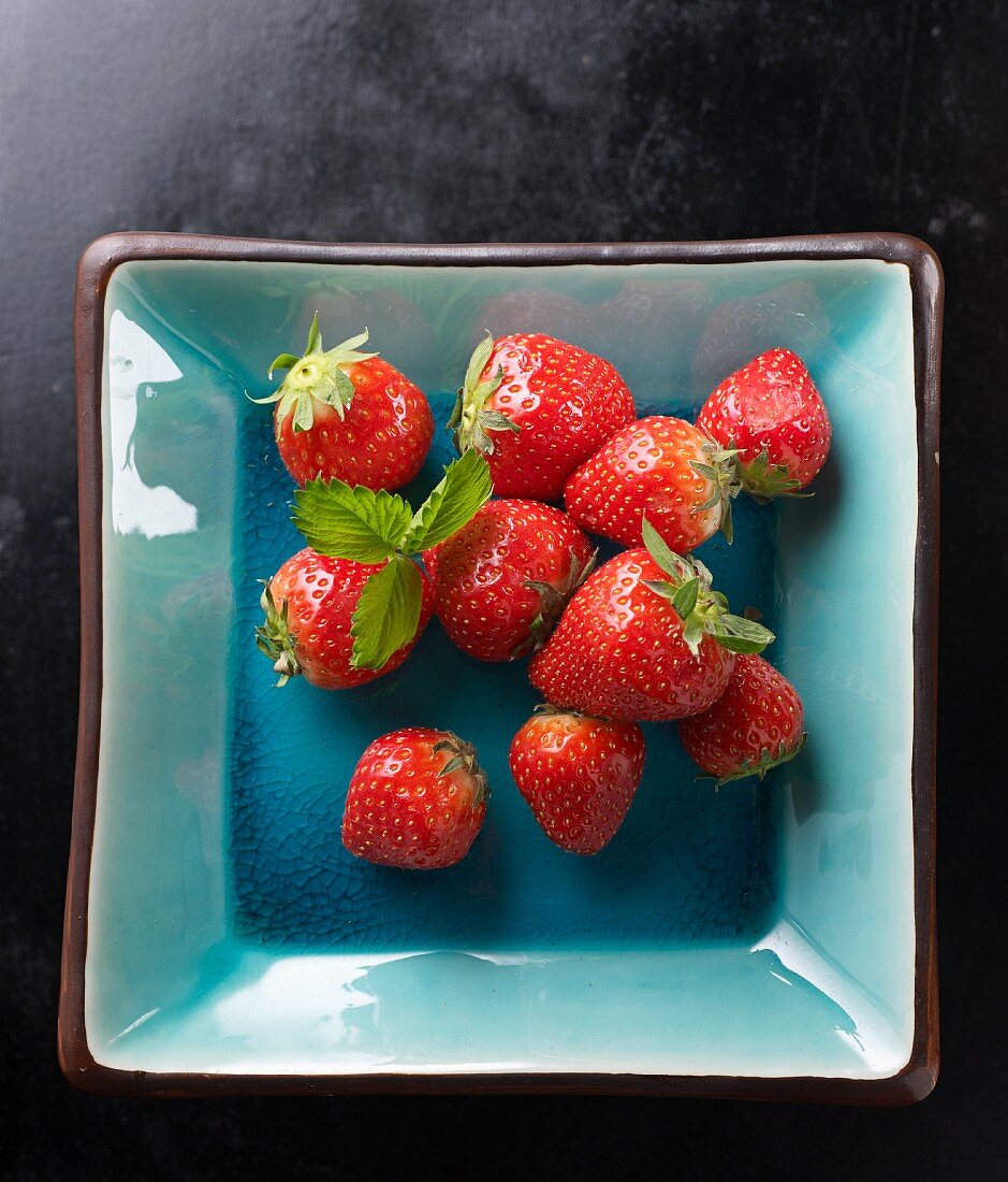 Fresh strawberries with leaves in a ceramic bowl