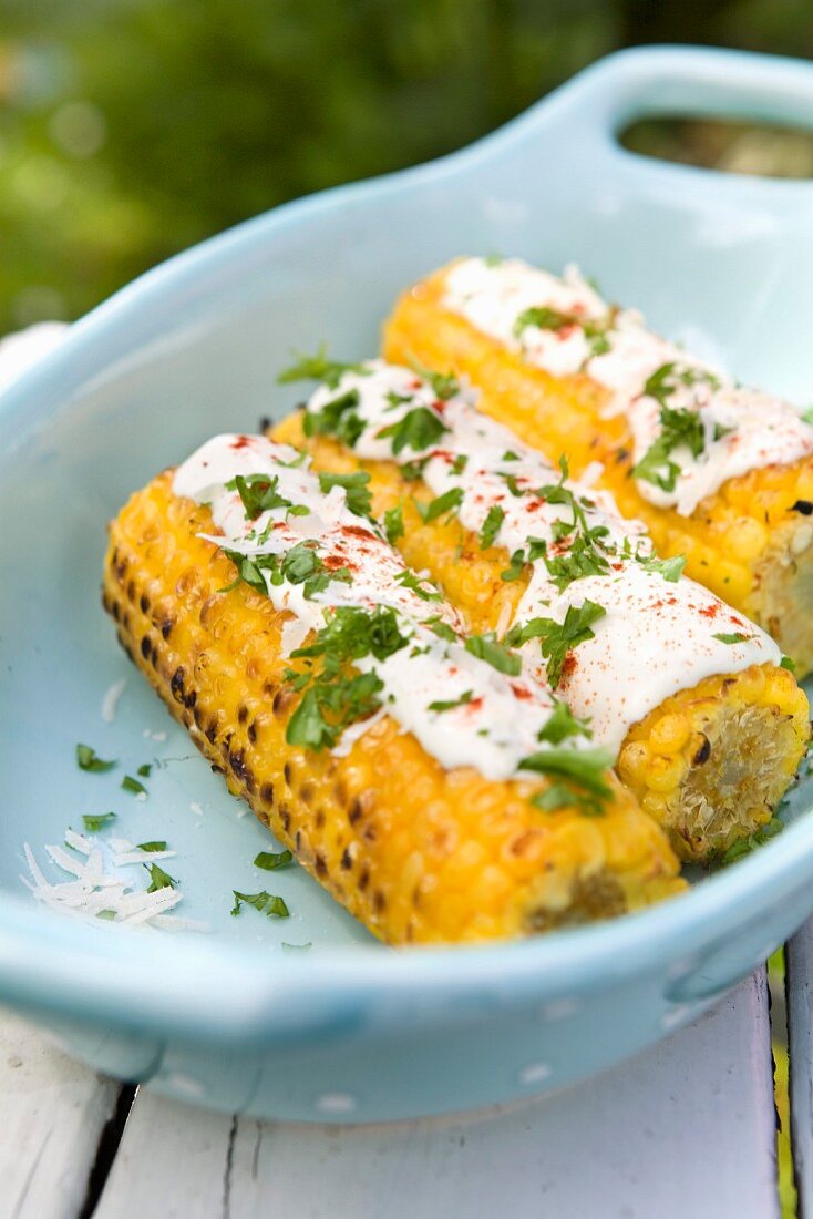 Gegrillte Maiskolben mit Sauce und Petersilie