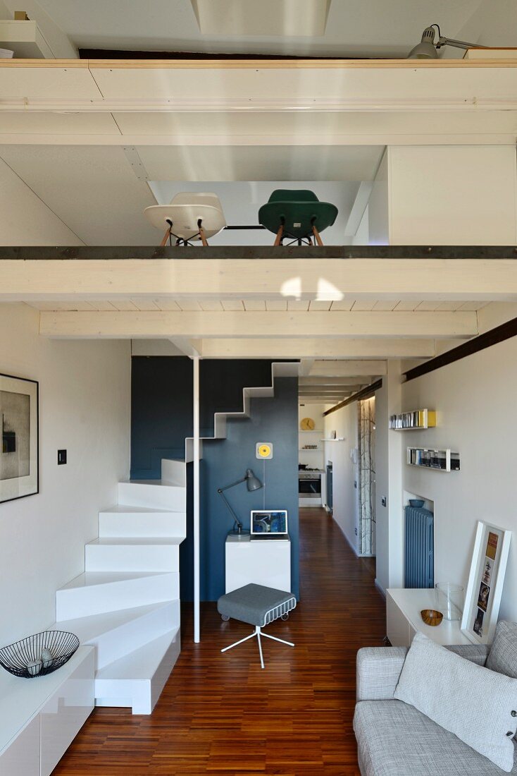 Offener Wohnraum mit gewendelter, weisser Treppe zur Galerie, mit Glasbrüstung