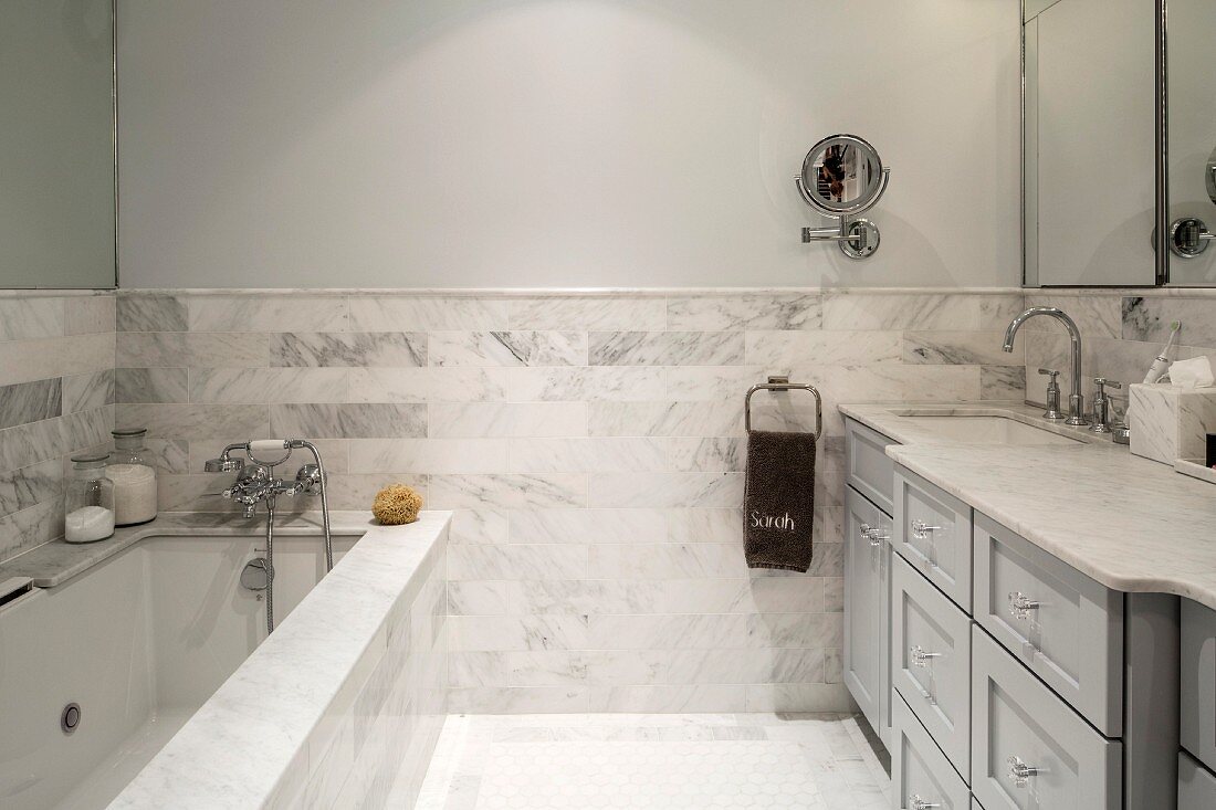 Bathroom with marble wall tiles, washstand counter and bathtub cladding