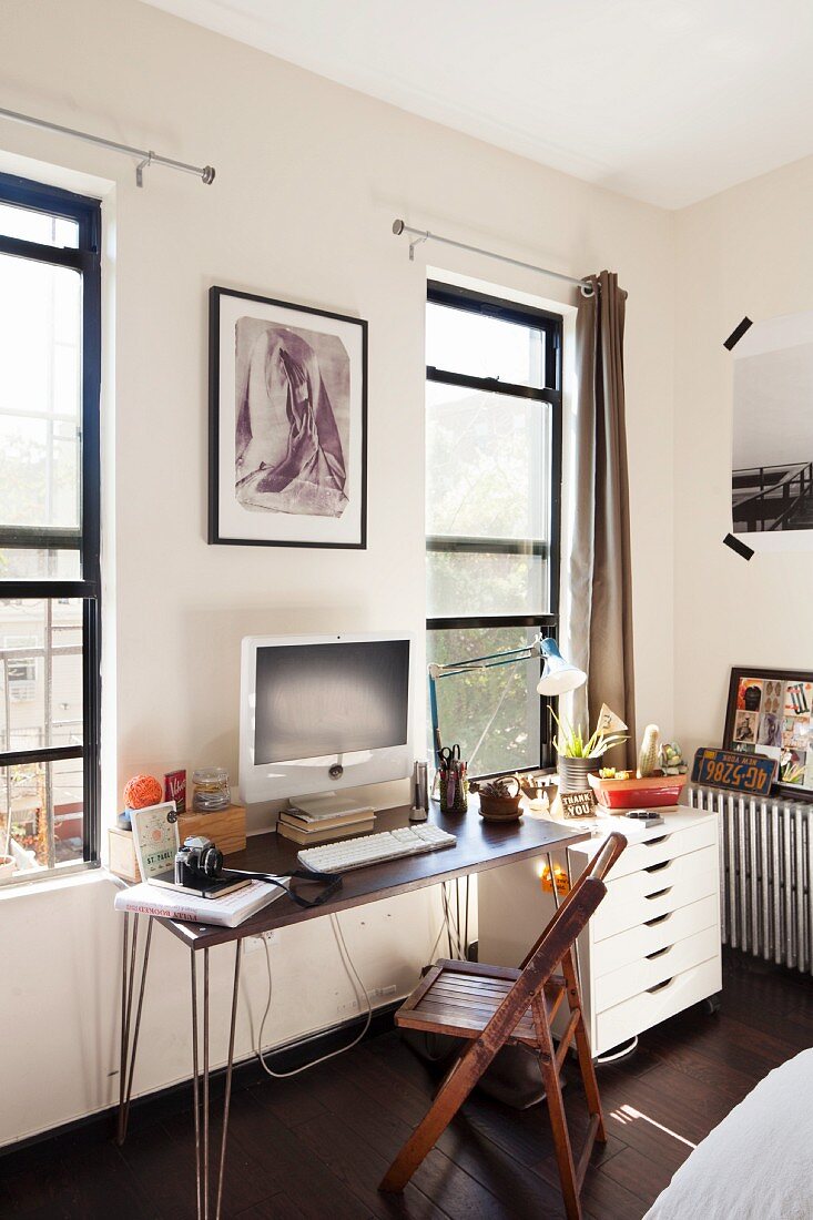 Desk between two windows next to white filing cabinet