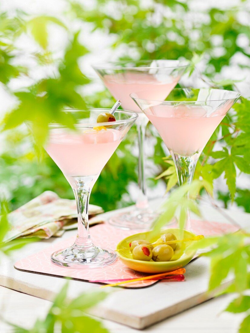 Three martinis with pink grapefruit juice and olives