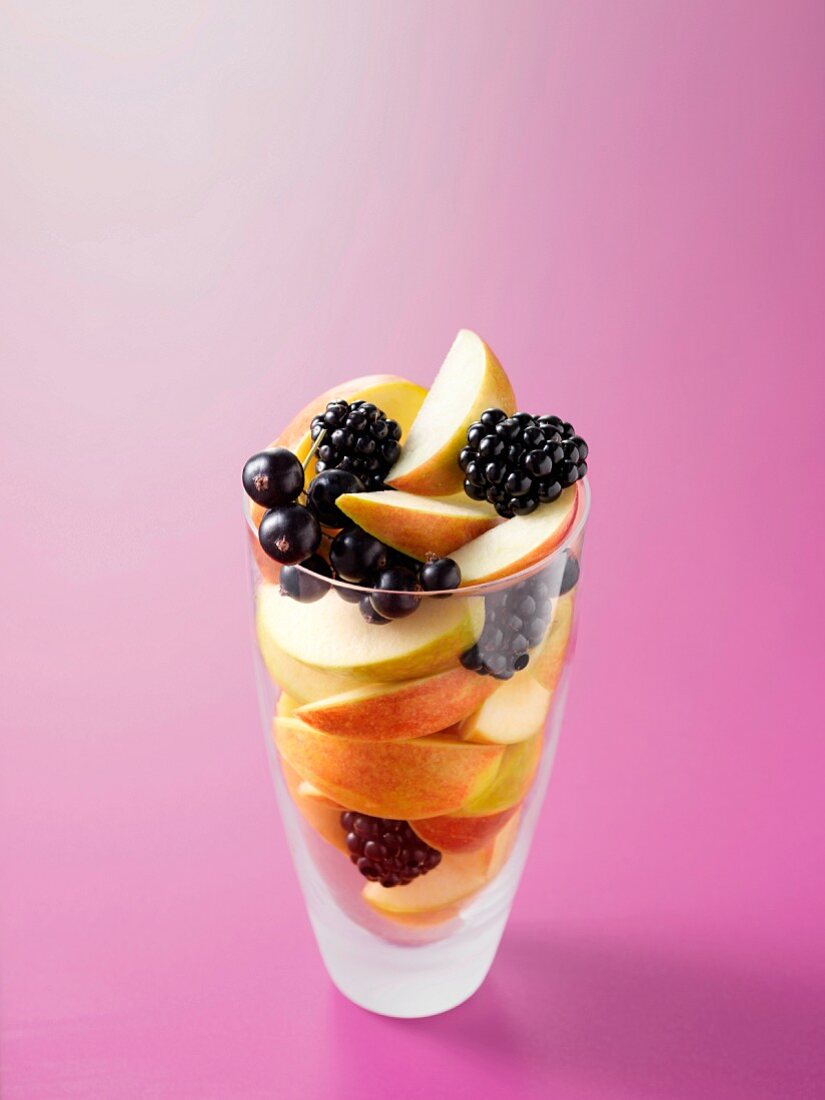 Ingredients for fruit juice with apples, black currants and blackberries in a glass