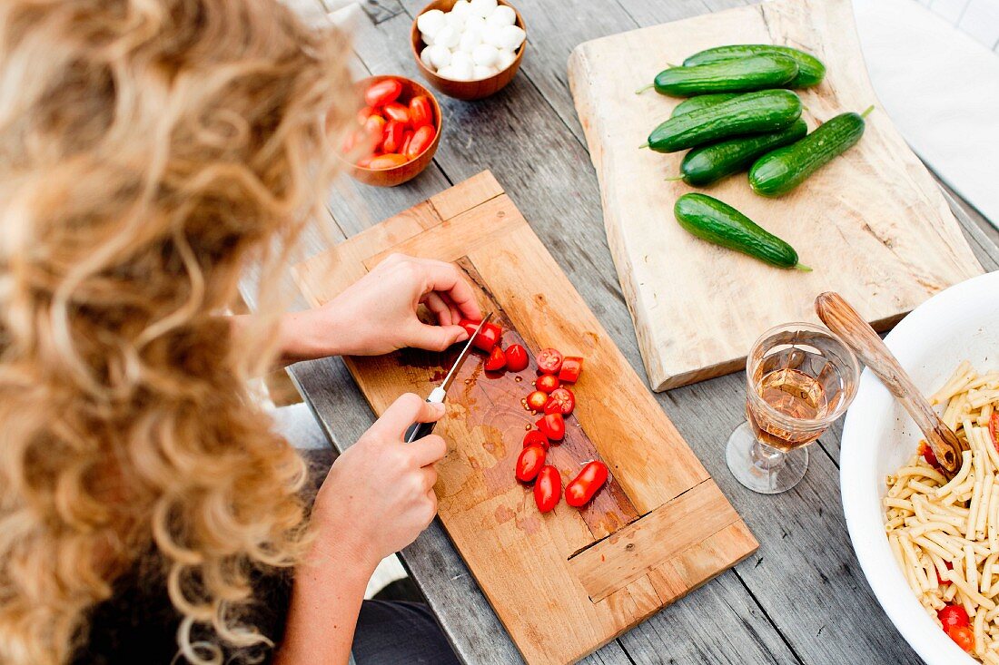 A woman slicing date tomatoes on a wooden chopping board