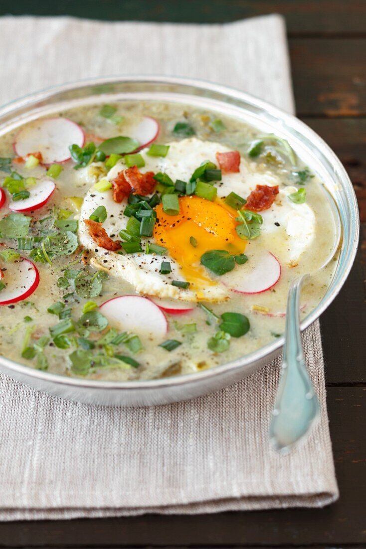 Sorrel and watercress soup with potatoes, fried egg, bacon and radishes