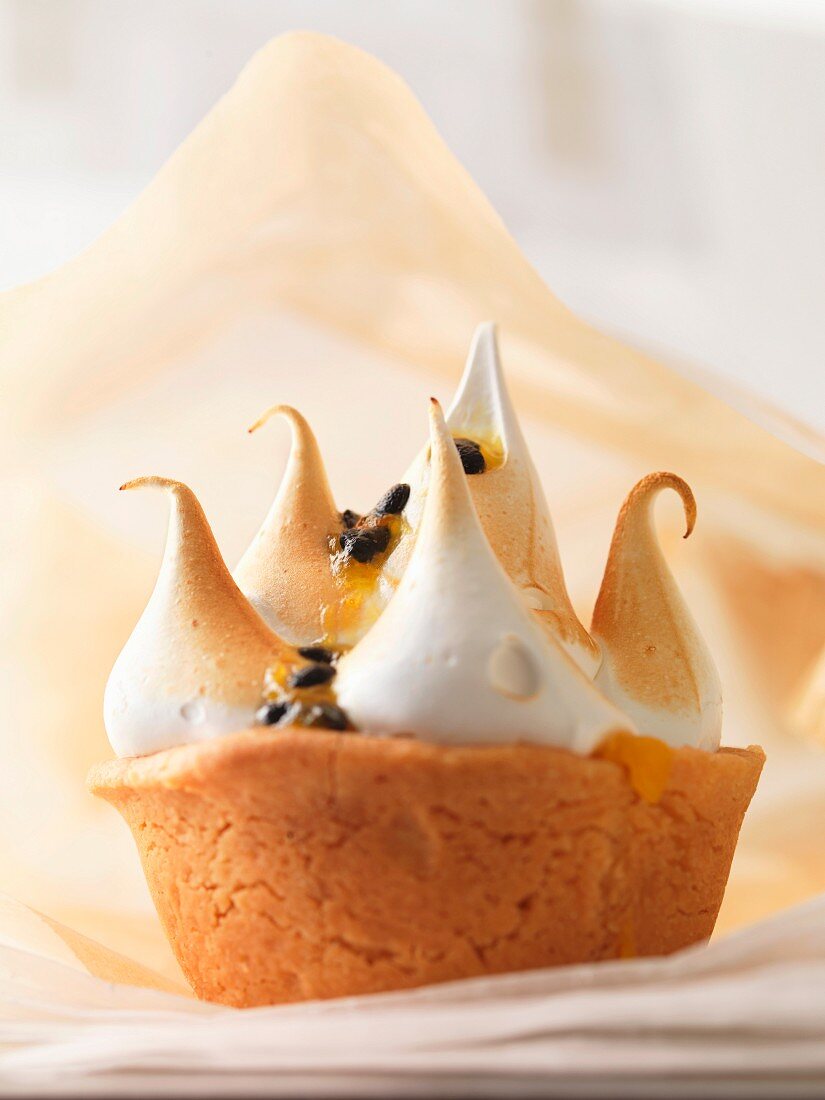 A mini cake topped with meringue and passion fruit sauce