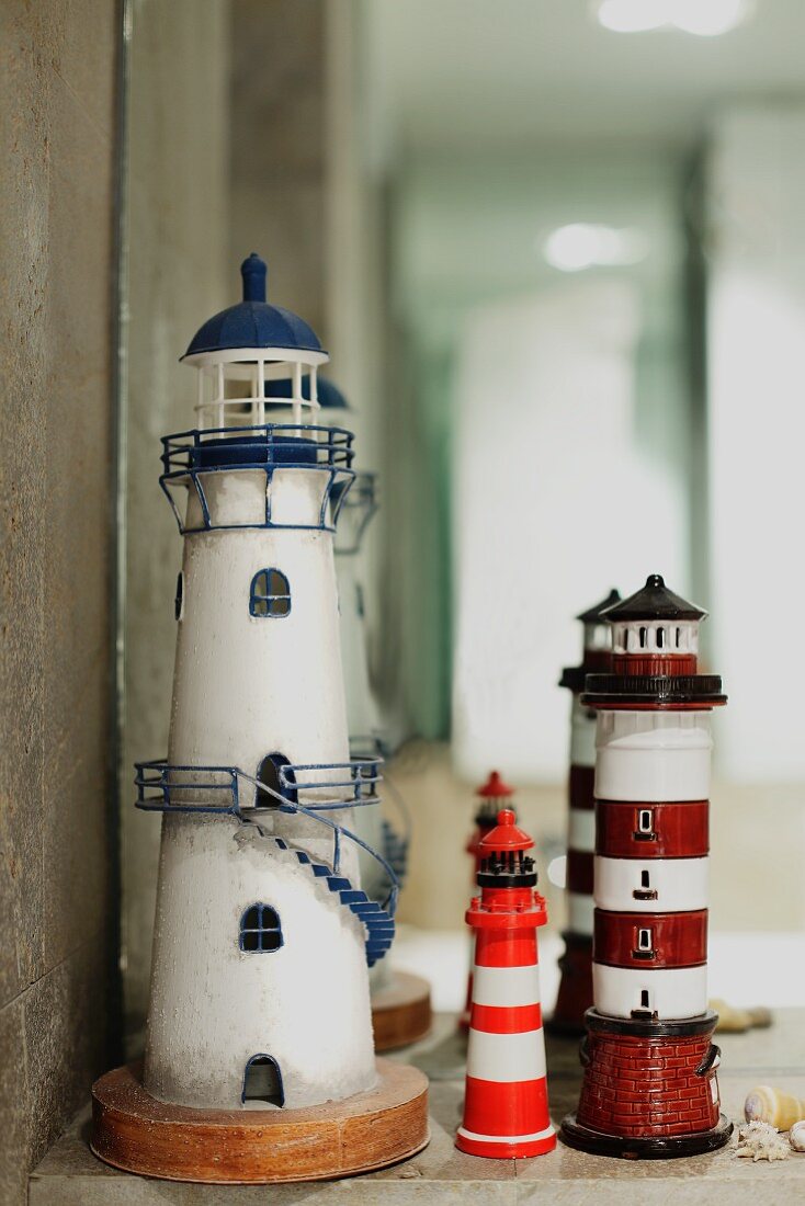 Three lighthouse ornaments in front of mirror