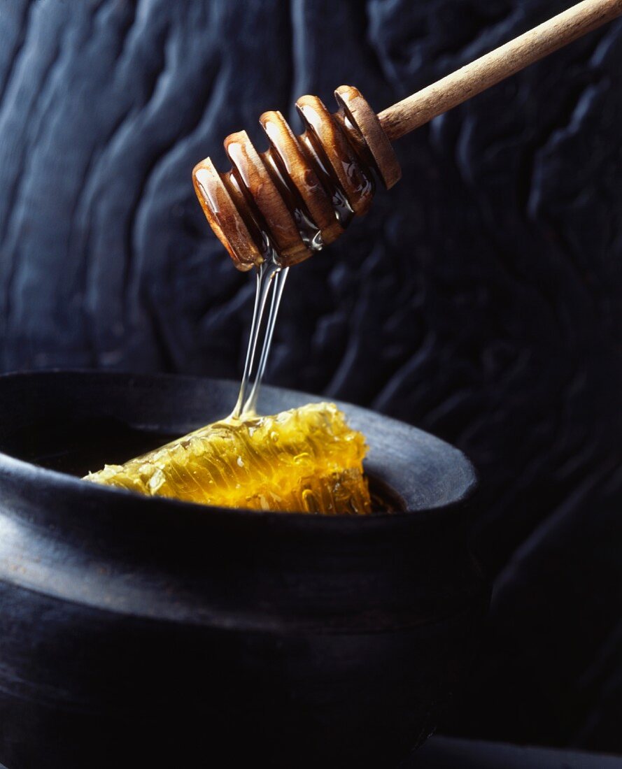 Honey flowing from a spoon onto a honeycomb