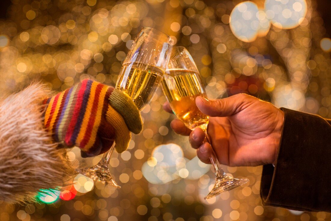 People toasting with champagne with Christmas lights in the background