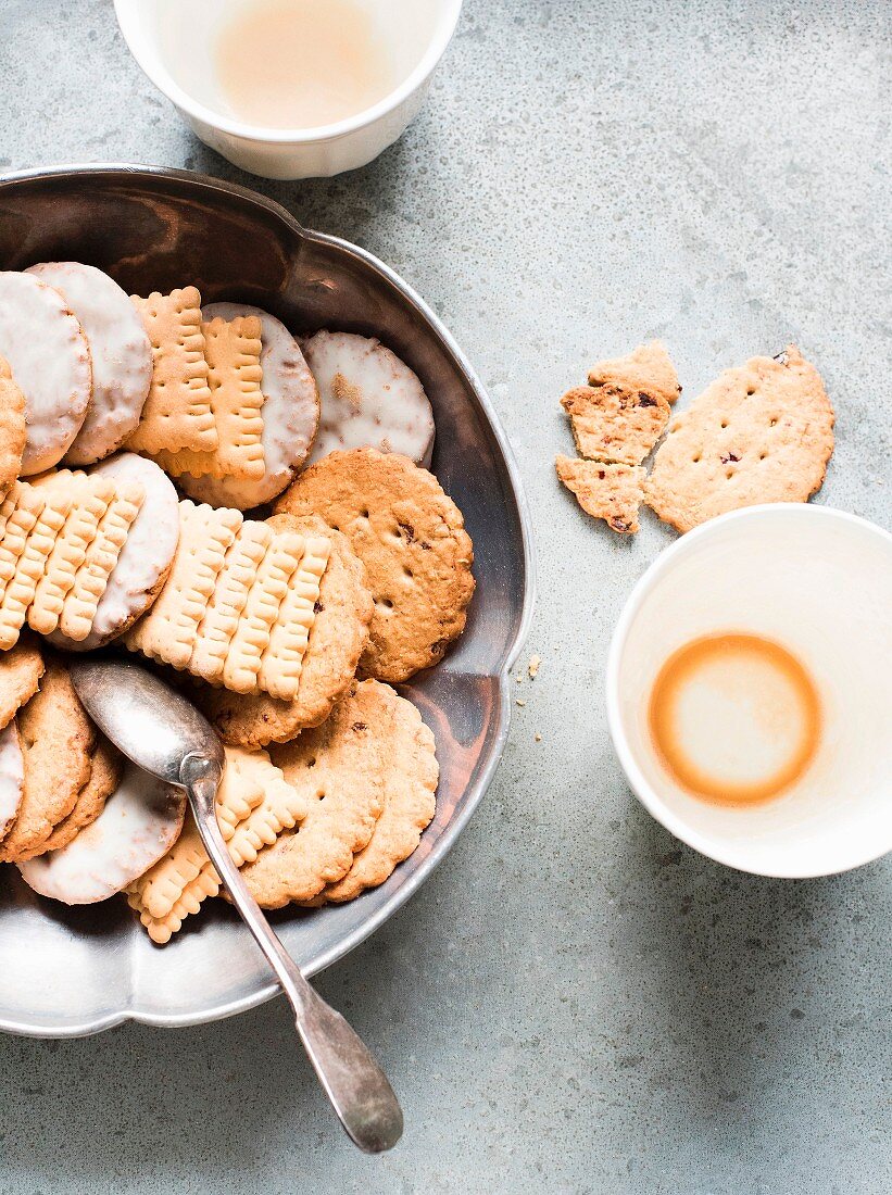 Biscuits in a metal tin with empty cups of tea