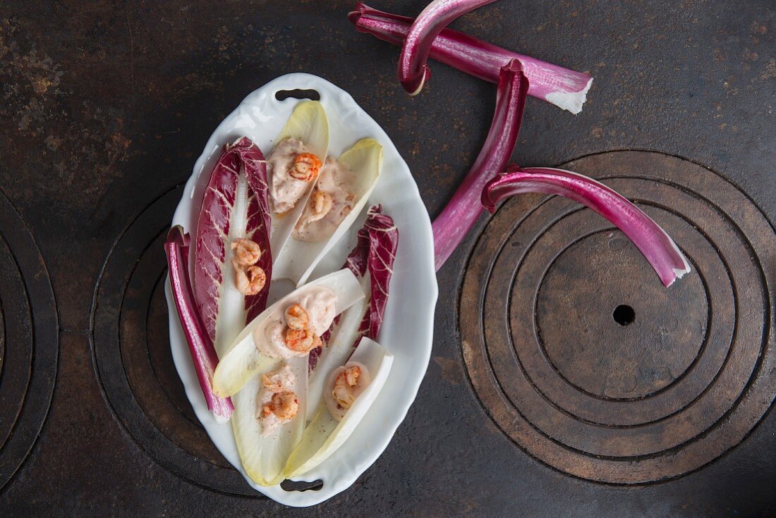 Chicory and radicchio with crab mayonnaise and shrimps in a porcelain bowl on a cast-iron pan