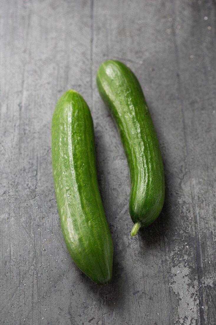 Two cucumbers on a grey surface