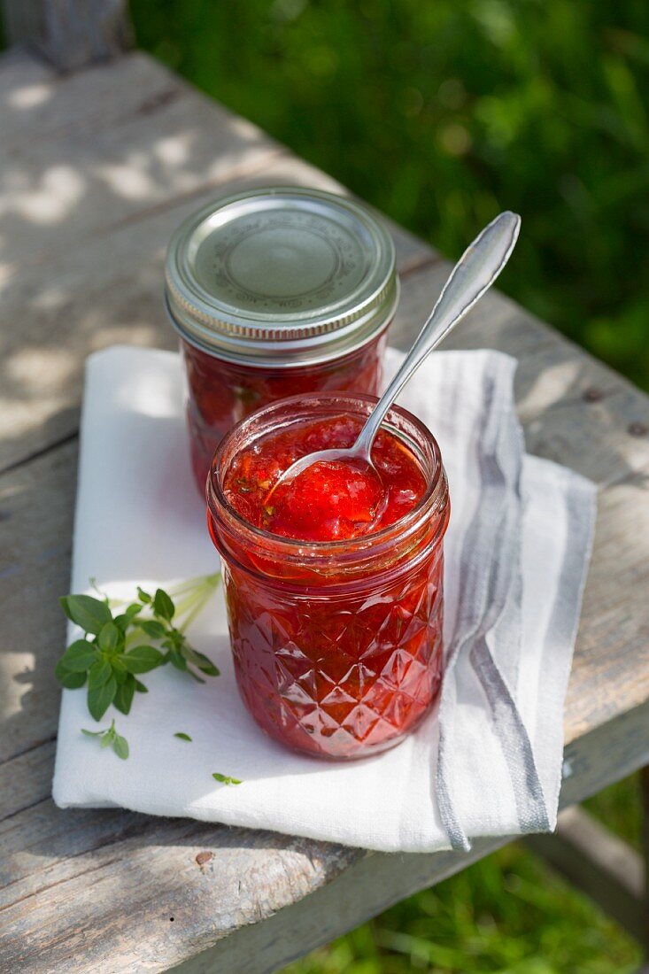 Erdbeermarmelade mit Basilikum auf Tisch im Freien