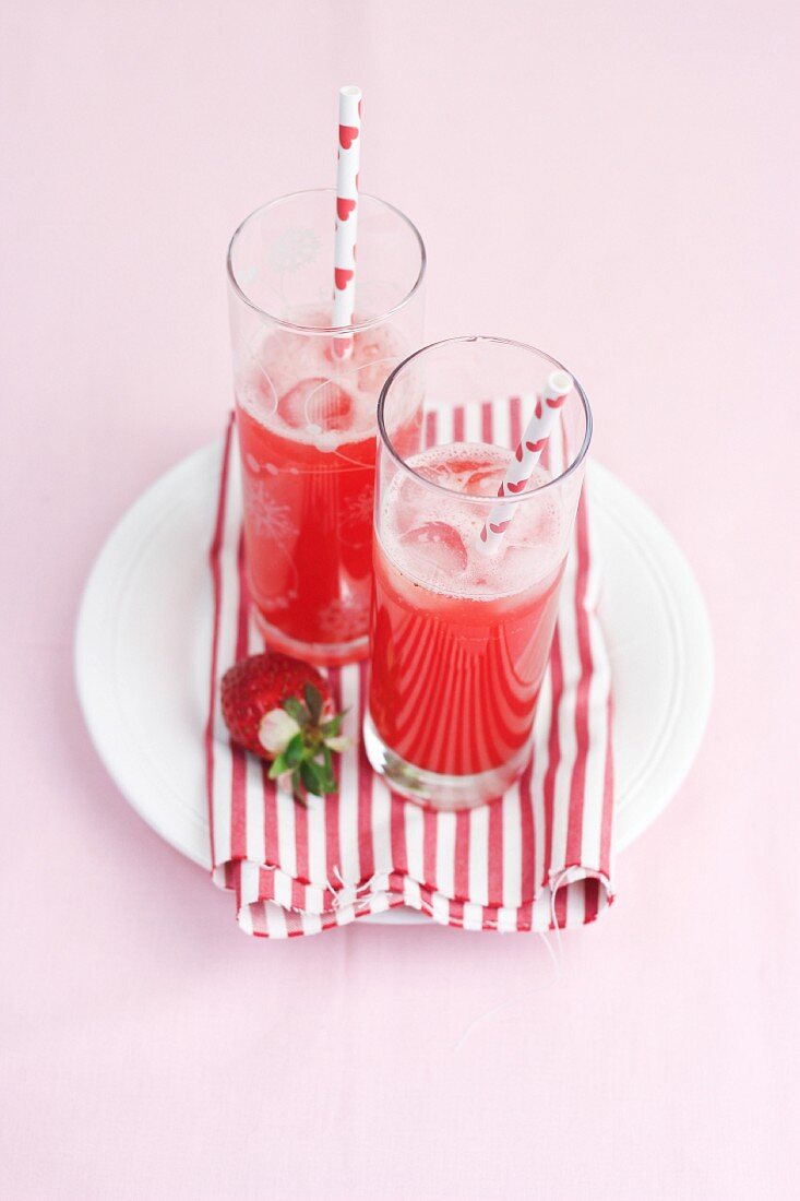Two glasses of raspberry lemonade with straws