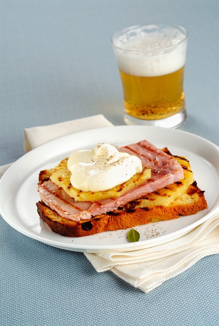 A slice of grilled panettone topped with pineapple, ham and sour cream