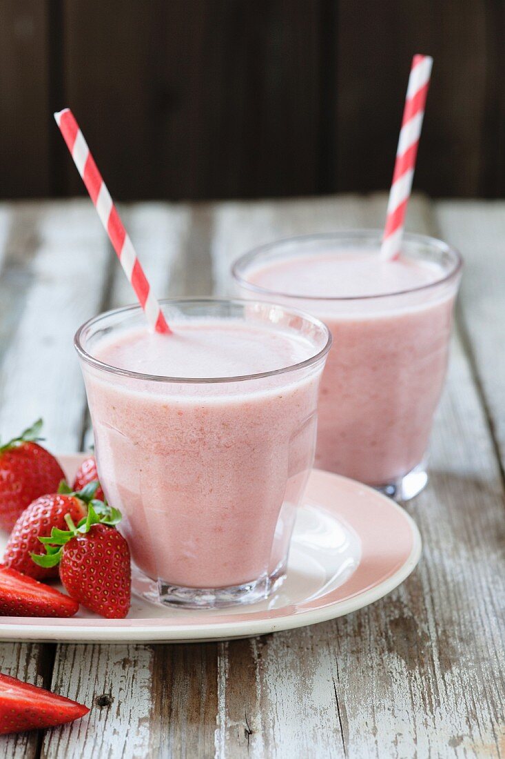 Fruit Smoothie in Glass with Drinking Straw Garnished with Strawberry
