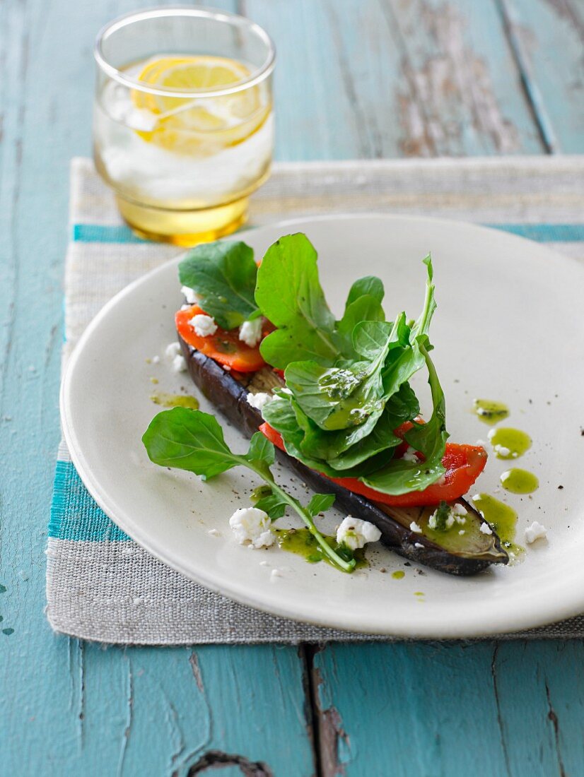 An open aubergine sandwich topped with pepper and feta cheese