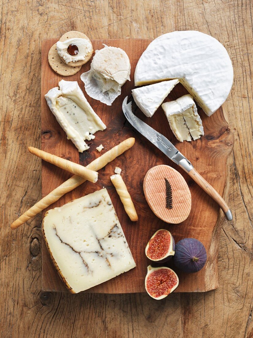 Different types of cheese with grissini, crackers and figs
