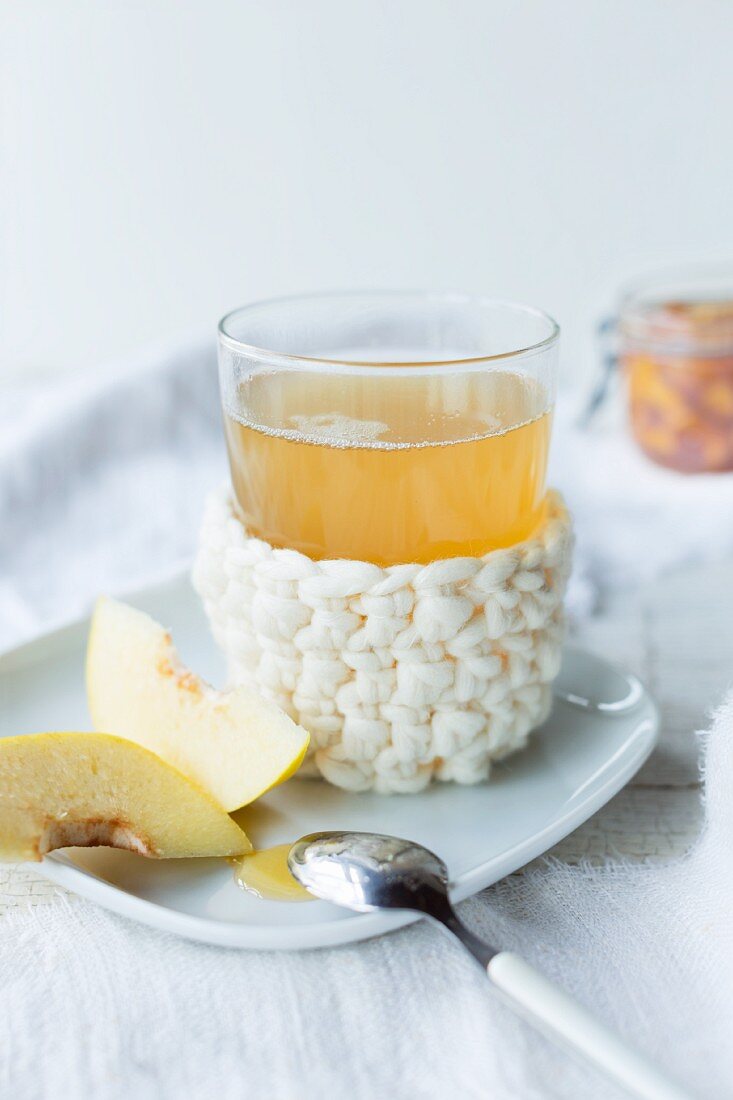 Quince tea with fresh quince pieces and a handmade crochet sleeve