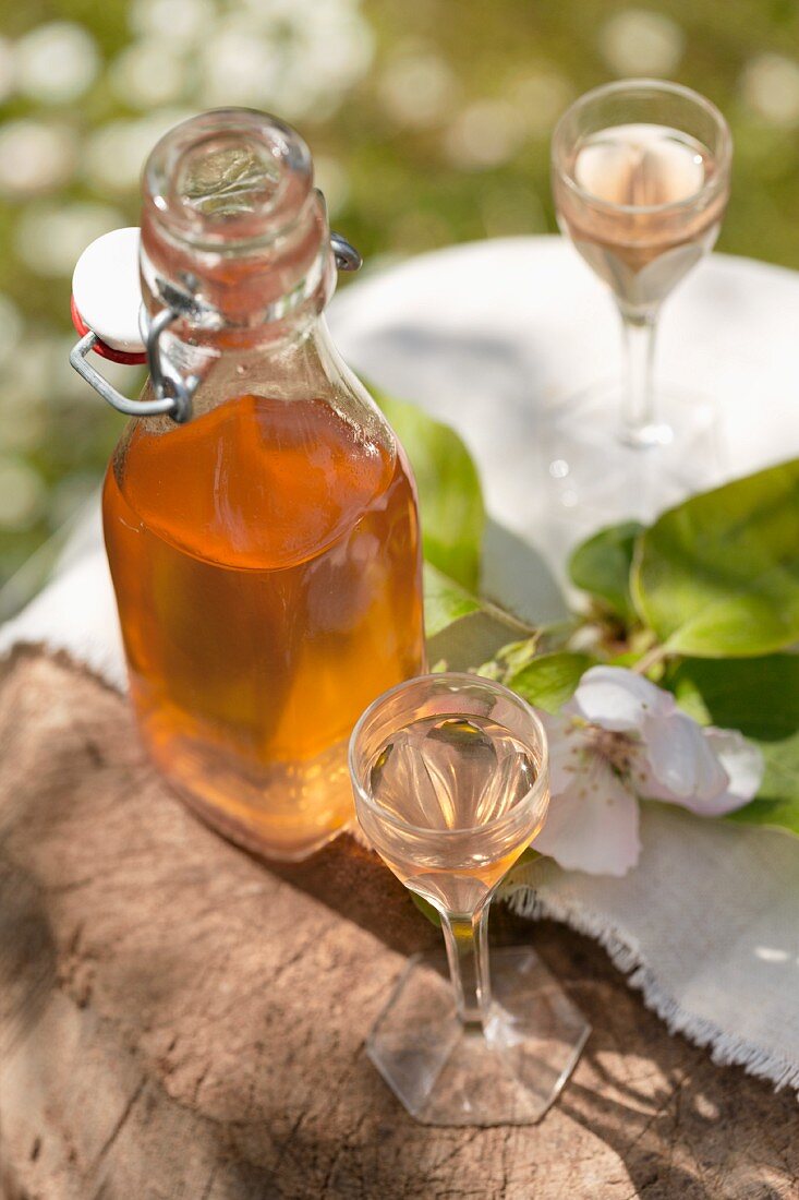 Quince schnapps in a bottle and small glasses on an old wooden block