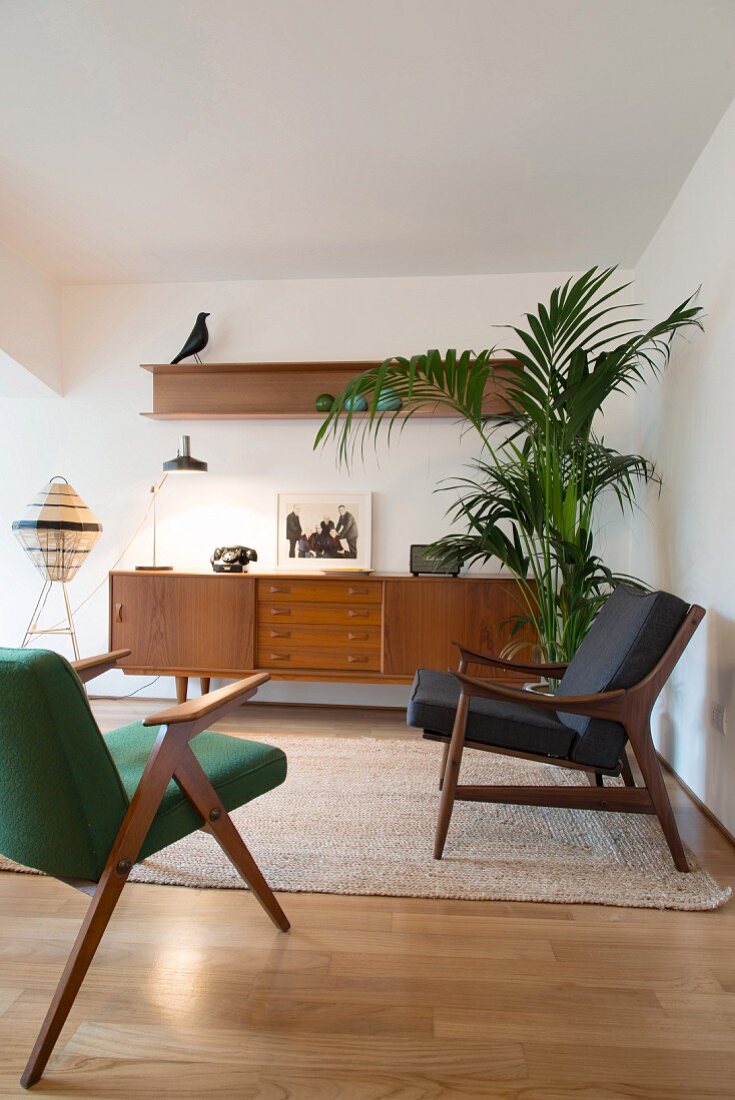 Retro armchair in front of sideboard and potted palm in living room