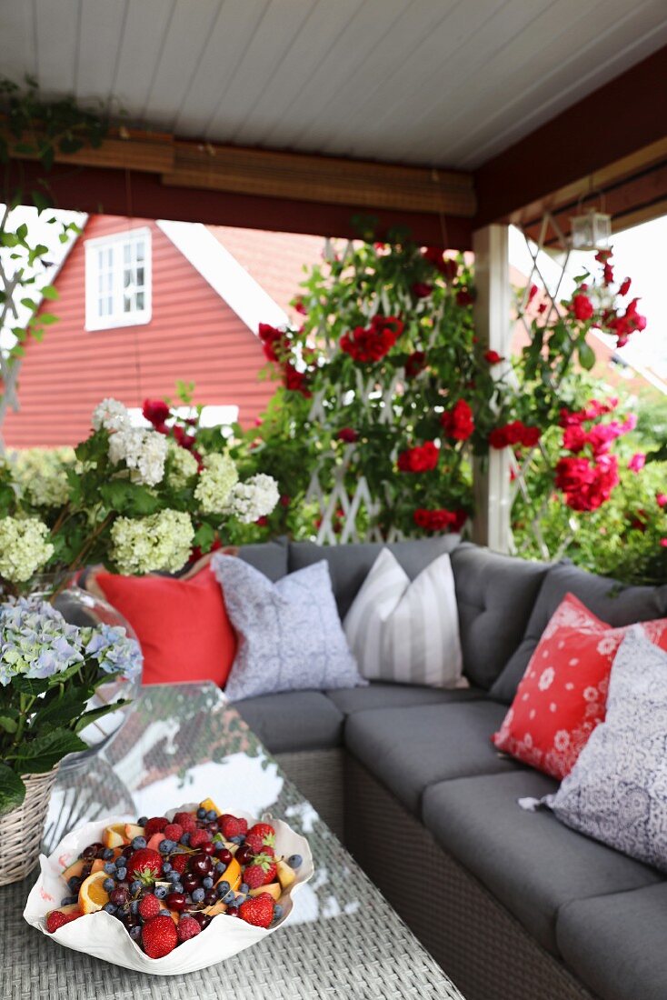 Scatter cushions arranged on grey corner sofa and fruit bowl on table