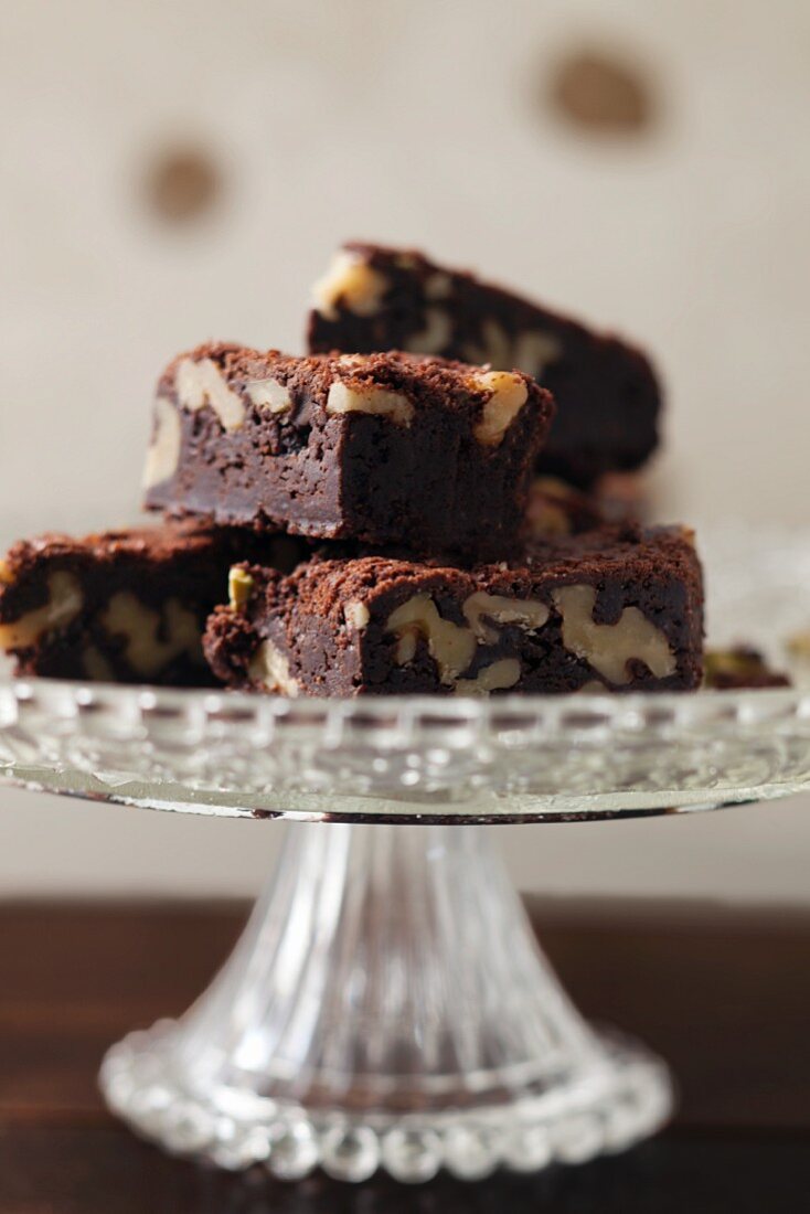 A pile of walnut brownies on a cake stand