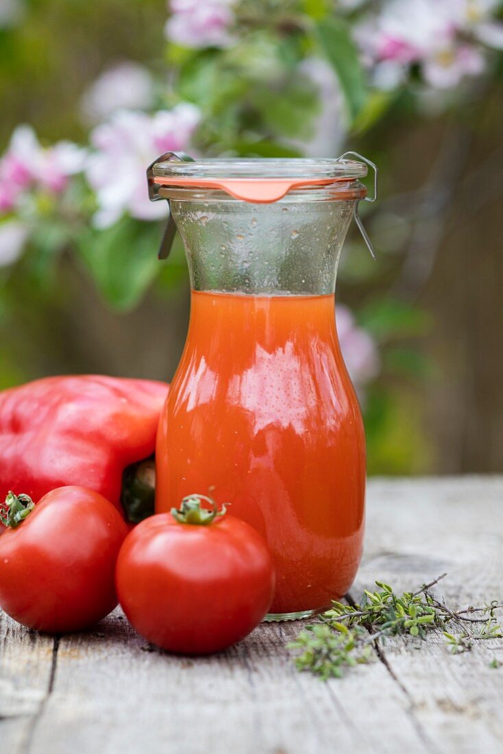 Gekühlter roter Paprika-Tomatendrink auf Tisch im Freien