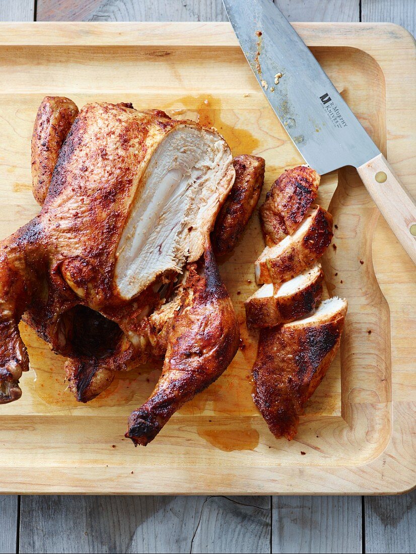 Carved grilled chicken on a chopping board (seen from above)