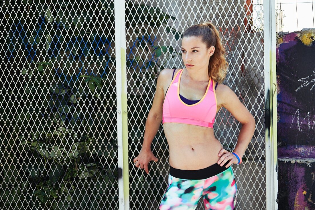A woman wearing sports clothing in front of a fence
