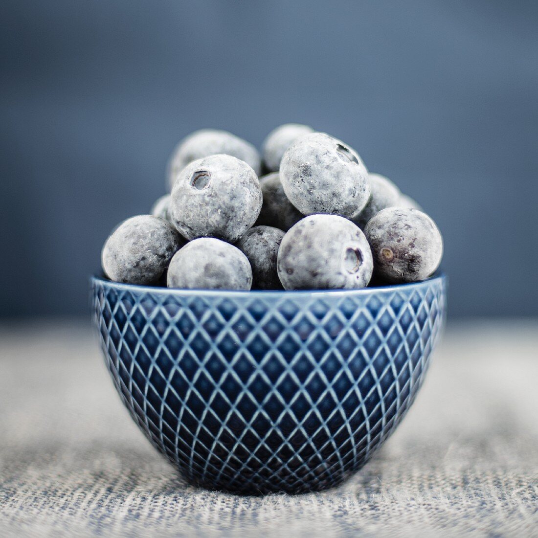 Gefrorene Blaubeeren in blauem Schälchen (Nahaufnahme)