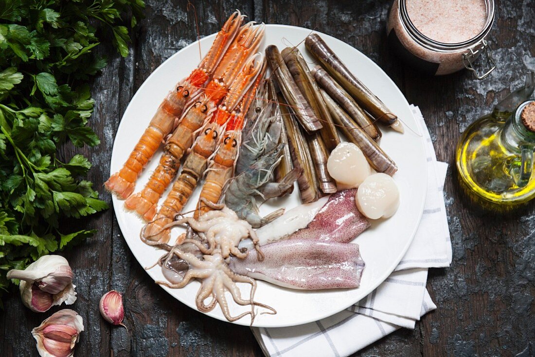 Various types of seafood on a plate with olive oil, herbs and garlic