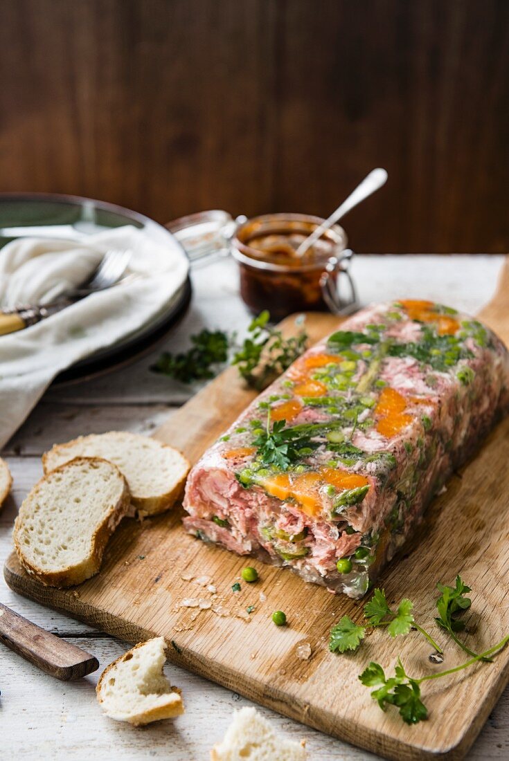 Ham hock terrine on a chopping board with bread and chutney