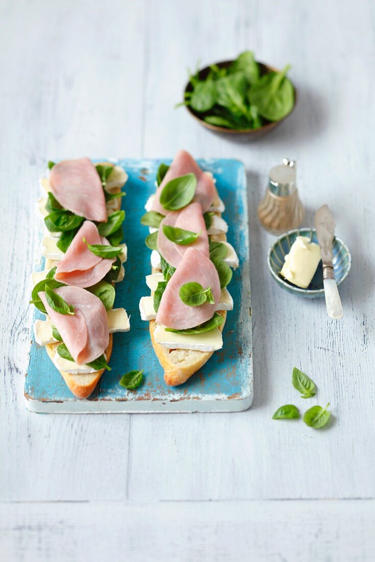 Open baguette sandwiches topped with spinach, basil, ham and Camembert
