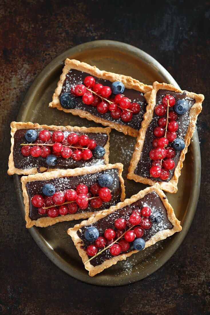 Rectangular tartlets with chocolate, redcurrants and blueberries