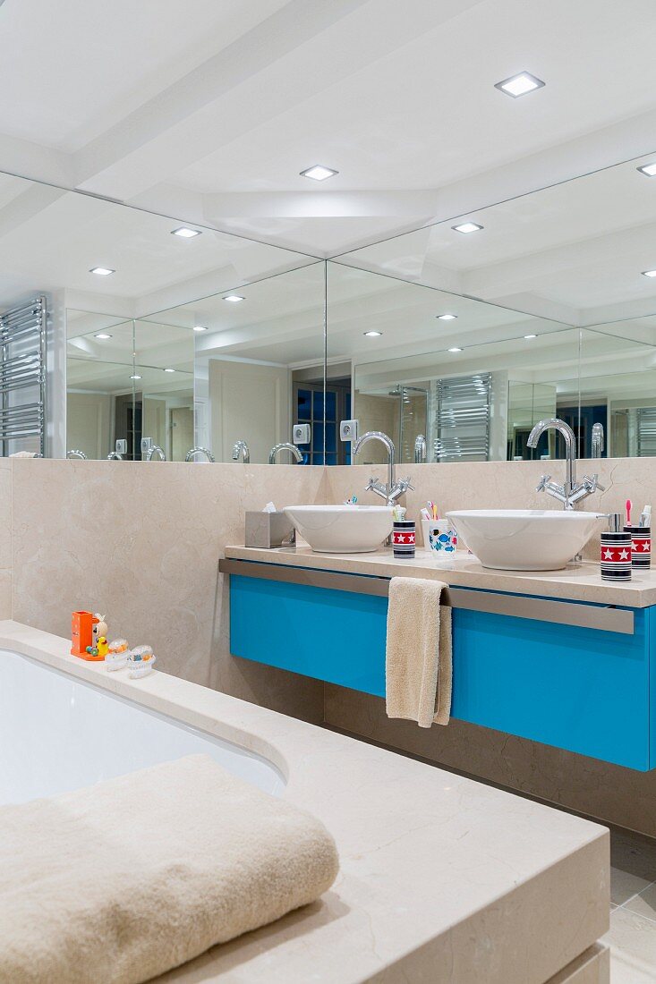 Custom washstand with light blue front and twin countertop basins below mirrored section of wall