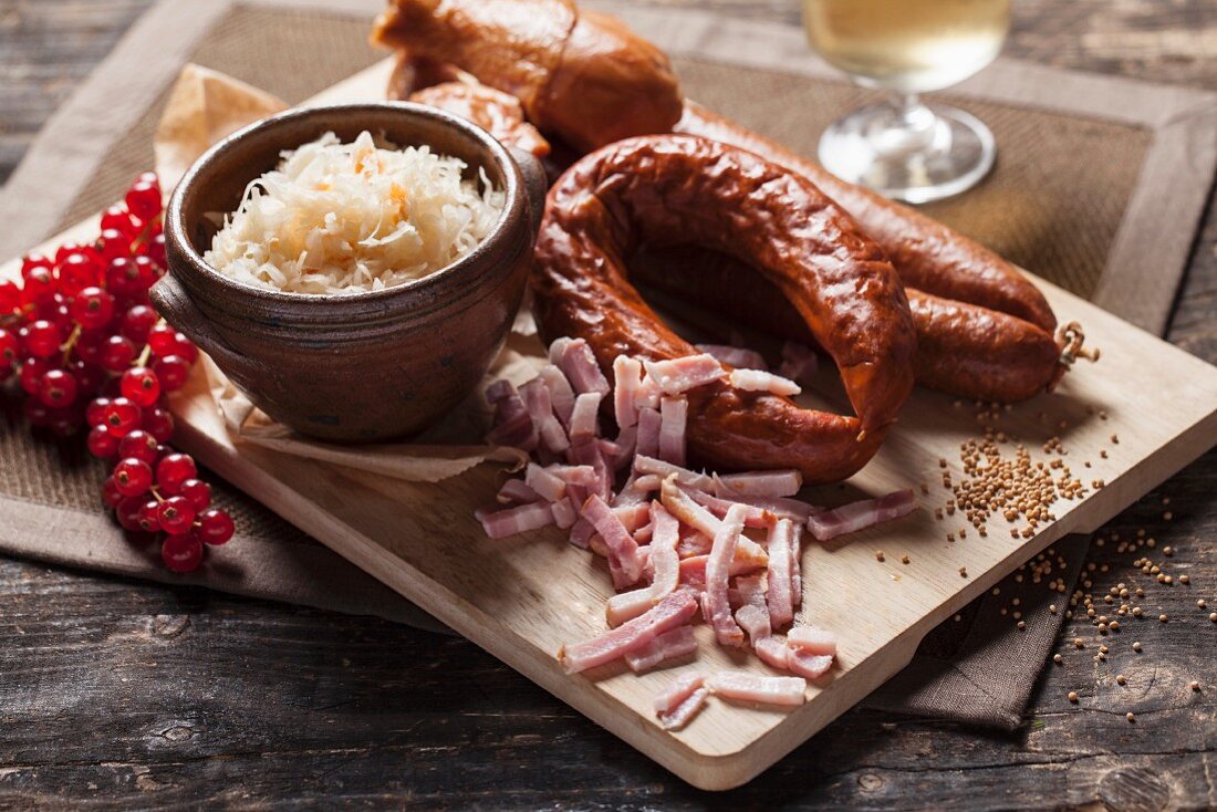 Sausages, sauerkraut and bacon strips on a wooden chopping board