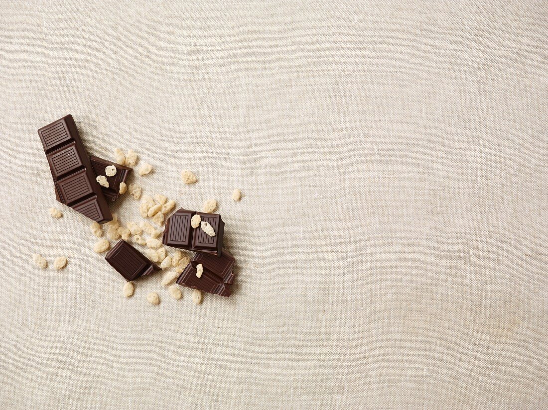 Zartbitterschokolade und Cerealien-Crunch auf weisser Tischdecke