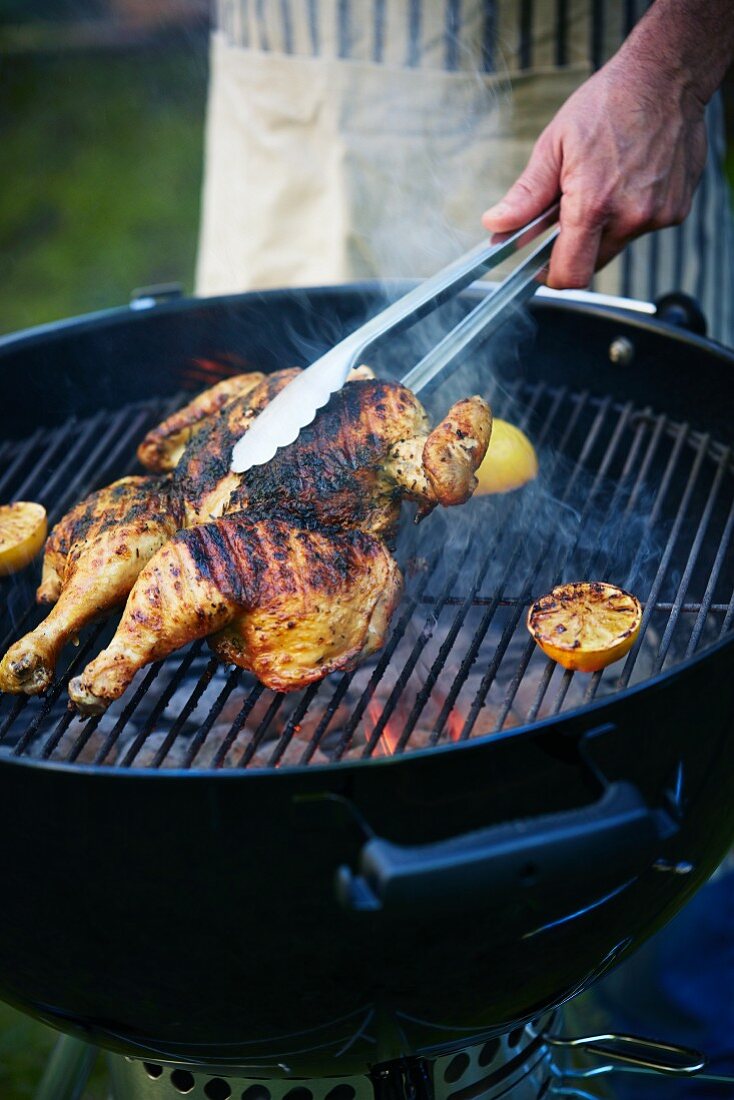 Chicken legs and lemon halves being grilled