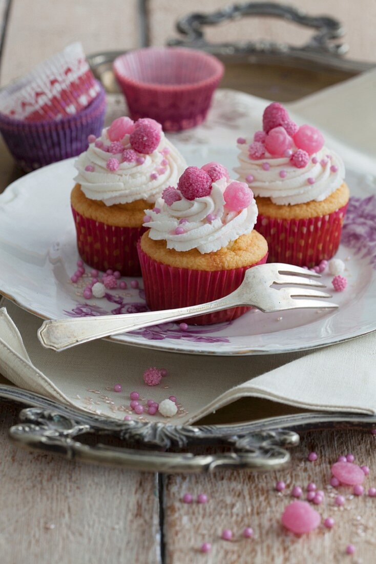 Geburtstags-Cupcakes mit rosa Zuckerblumen und gefrorenen Erdbeeren