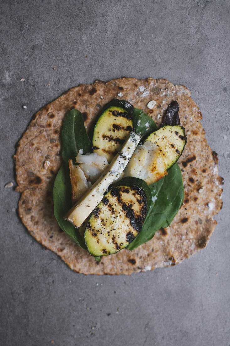 A wholemeal tortilla topped with grilled vegetables and cheese